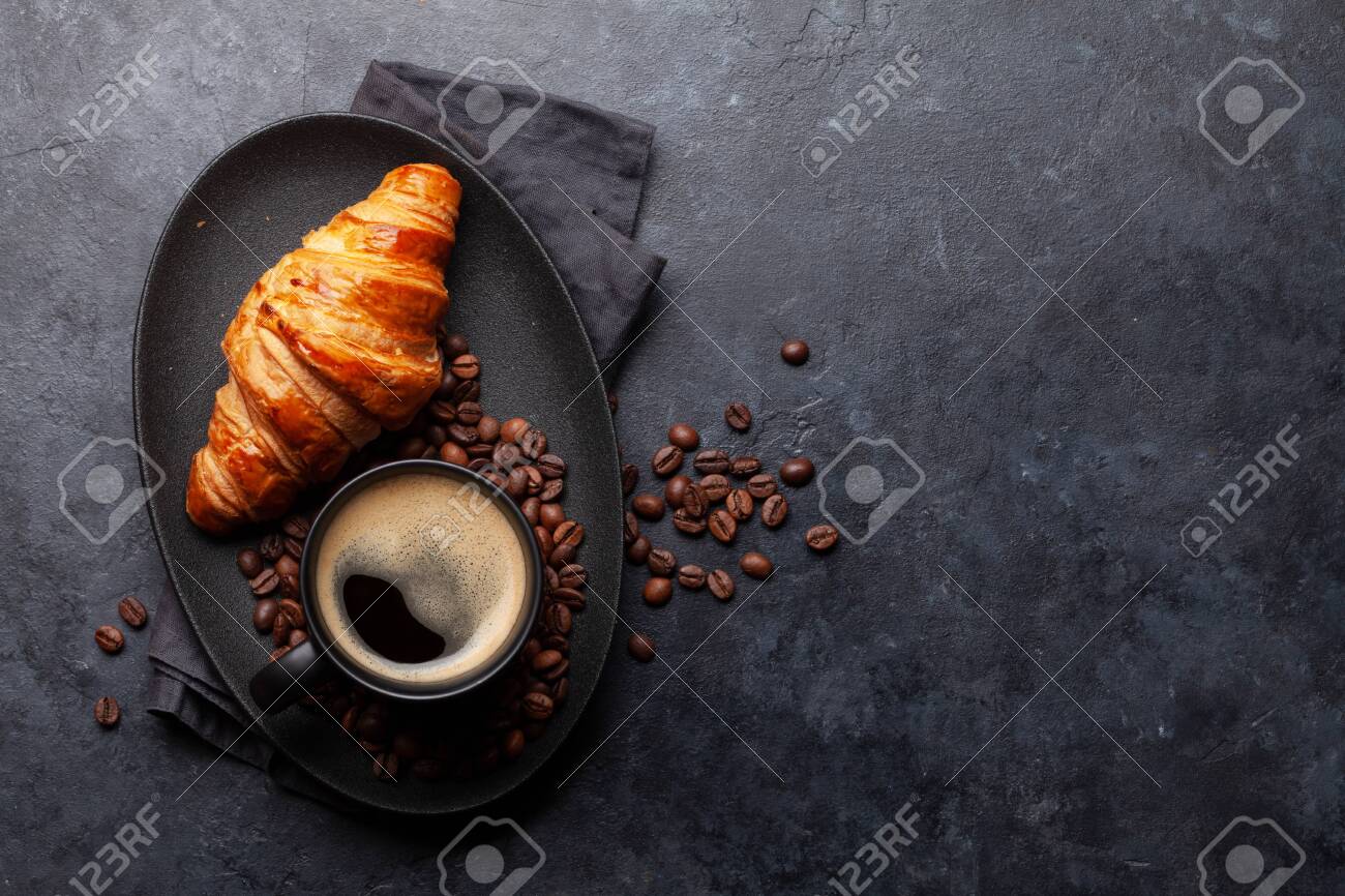 Espresso coffee and croissant for breakfast. Top view flat lay with copy space